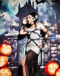 a woman in a halloween costume posing in front of a castle