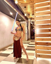 a woman in a star wars costume posing with a light saber