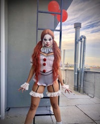 a woman dressed as a clown posing on a ladder